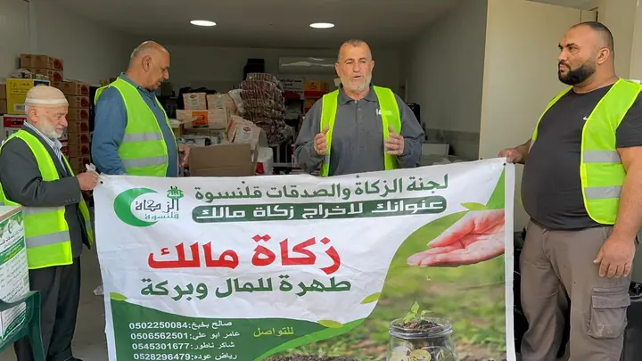 متطوعو اللجنة يحملون لافتة زكاة مالك